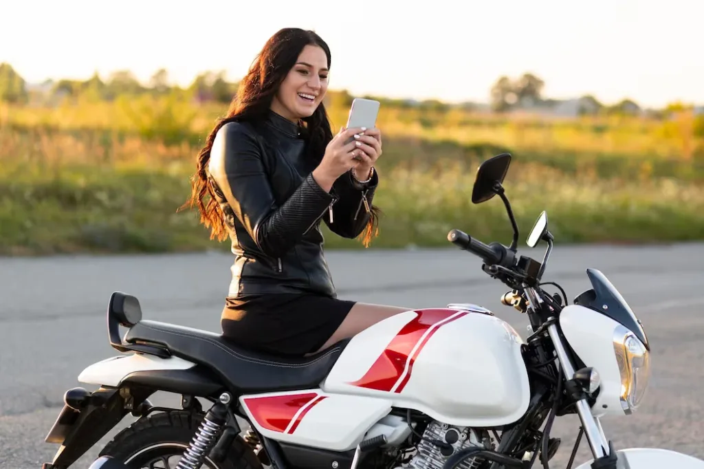 side view smiley woman looking smartphone while sitting her motorcycle 23 2148685253