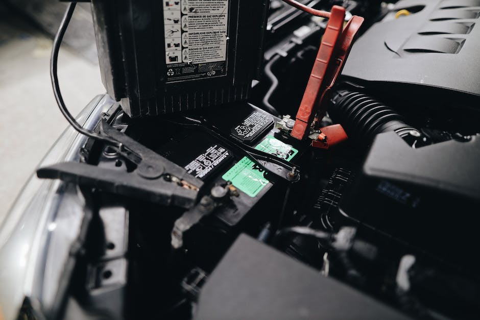 Image of car battery terminals with red and black cables connected to them.